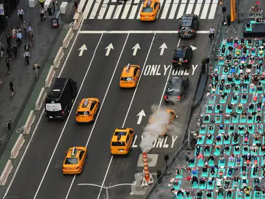 Sejumlah orang melakukan yoga bersama di kawasan Times Square, New York pada 'Summer Solstice' atau hari dengan siang terpanjang di musim panas, Rabu (21/6). Acara tersebut menandai Hari Yoga Internasional yang jatuh pada 21 Juni. (TIMOTHY A. CLARY/AFP)