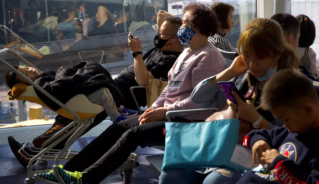 Para pelancong yang mengenakan masker menunggu penerbangan mereka di Bandara Internasional Hong Kong di Hong Kong, Selasa (21/1/2020). Masker terjual habis dan pemeriksaan suhu di bandara dan stasiun kereta api menjadi norma baru di China menyusul merebaknya wabah virus corona.  (AP/Ng Han Guan)