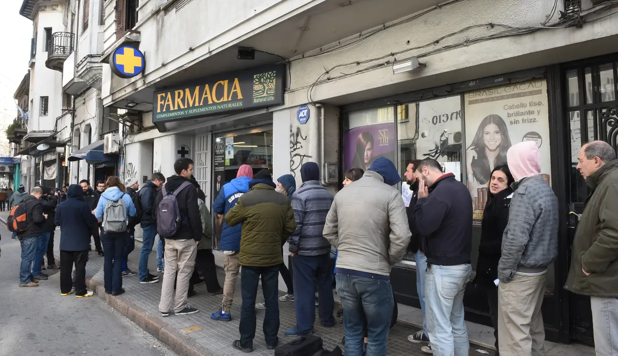 Orang-orang berbaris mengantre di depan apotek untuk membeli ganja di Montevideo, Uruguay (19/7 Apotek ini menjual ganja tersebut seharga USD 6,5 atau berkisar Rp 86.000 per lima gram. (AFP Photo/Miguel Rojo)