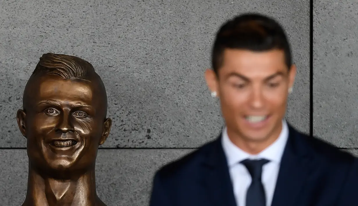 Bintang Timnas Portugal, Cristiano Ronaldo berdiri di samping patung perunggunya dalam seremoni peresmian Bandara Cristiano Ronaldo, di Funchal, Rabu (29/3). Bandara Madeira resmi berganti nama menjadi bandara Cristiano Ronaldo. (FRANCISCO LEONG/AFP)