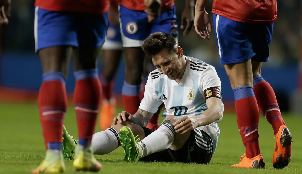 Lionel Messi duduk dilapangan dikelilingi oleh pemain Haiti saat pertandingan persahabatan di stadion Bombonera di Buenos (29/5). Pada pertandingan ini Argentina unggul 1-0 pada babak pertama melaui gol hasil penalti Lionel Messi. (AP / Natacha Pisarenko)