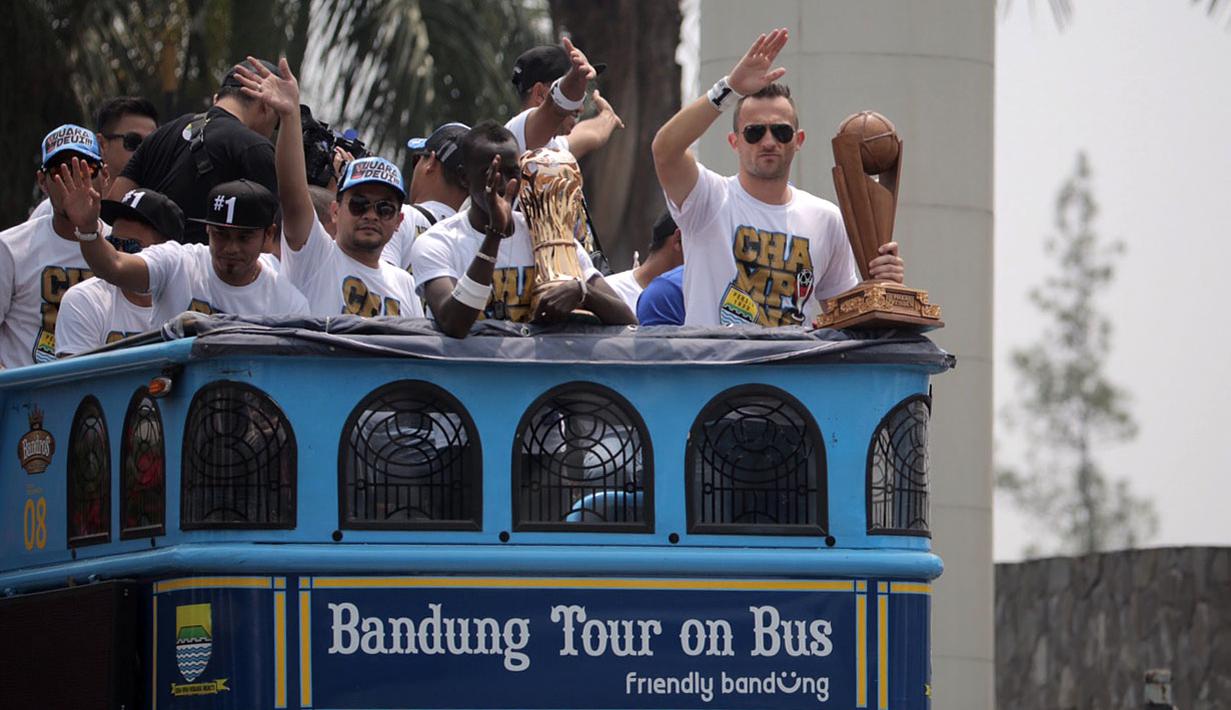Pemain Persib, Ilija Spasojevic (kanan) memegang Piala Presiden diatas Bus Bandung Tour on Bus (Bandros) dalam Pawai Persib Juara Piala Presiden saat start dari Kota Baru Parahyangan, Bandung, Minggu (25/10/2015). (Bola.com/Nick Hanoatubun)