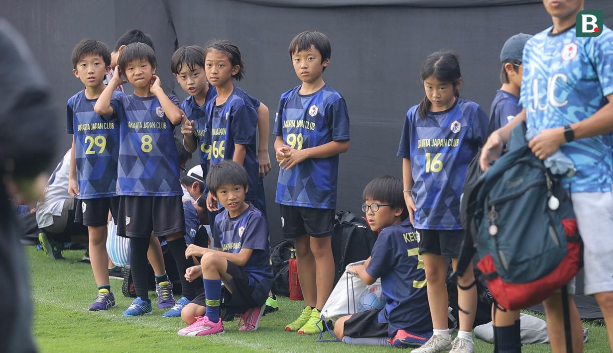 Sejumlah anak-anak yang tergabung ke dalam sekolah sepak bola Jakarta Japan Club (JJC) menunggu kedatangan para pemain Timnas Jepang sebelum melakukan sesi latihan yang berlangsung di Lapangan A, Senayan, Jakarta, Selasa (12/11/2024). (Bola.com/Bagaskara Lazuardi)