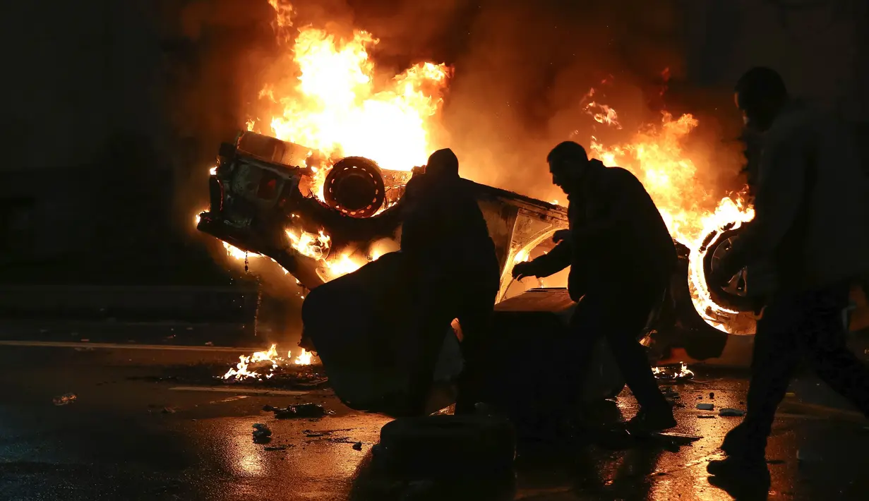 Pengunjuk rasa memindahkan tempat sampah di depan mobil polisi yang terbakar tidak jauh dari Gedung Parlemen Georgia, Tbilisi, Georgia, Kamis (9/3/2023). Partai Georgian Dream menyatakan keputusan menarik RUU "Agen Asing" adalah untuk meredakan konfrontasi dengan masyarakat. (AP Photo/Zurab Tsertsvadze)