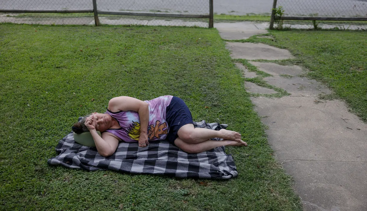 Dawn Borchert tidur di halaman depan rumahnya di sebuah lingkungan dekat 11th Street dan Lewis Ave, di Tulsa, Oklahoma, Selasa (20/6/2023). Borchert tidak memiliki listrik sejak badai akhir pekan dan tidur di tenda semalaman, tetapi pindah ke luar untuk menyejukkan diri pada pagi hari. (Mike Simons/Tulsa World via AP)