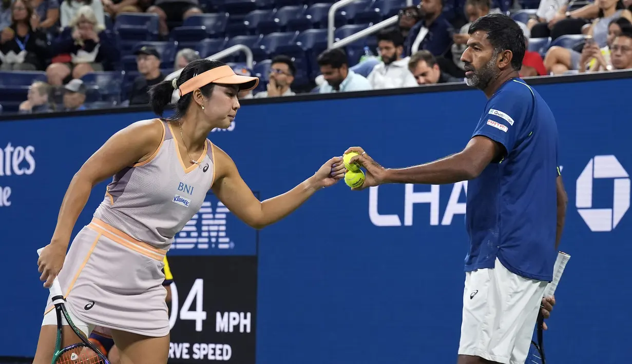 Petenis Indonesia, Aldila Sutjiadi (kiri) memberikan bola kepada petenis India, Rohan Bopanna saat bertanding melawan petenis ganda campuran Amerika Serikat, Taylor Townsend/Donald Young pada laga semifinal US Open 2024 yang berlangsung di di Stadion Louis Amstrong, New York, Amerika Serikat, Rabu (04/09/2024) WIB. (AP Photo/Eduardo Munoz Alvarez)