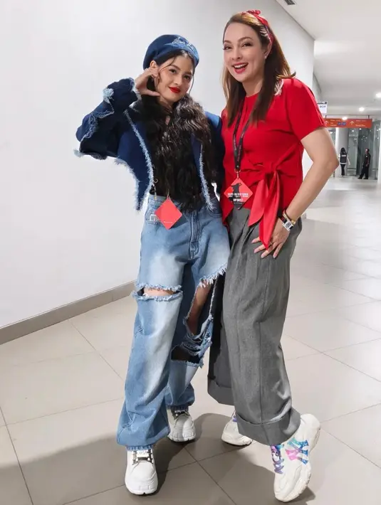 Reisa Broto Asmoro tampil dengan gaya kasual edgy. Ia memadukan blus merah menyala dengan aksen pita di pinggang, loose pants abu-abu, serta sneakers putih. Penampilannya semakin manis dengan bandana merah yang senada dengan blusnya.