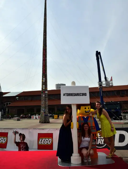 Sejumlah warga berpose di depan sebuah menara lego setinggi 35.50 meter, Itali, Minggu (21/6/2015).  Menara ini dibangun oleh ribuan relawan menggunakan sekitar 580.000 lego dan mendapat sertifikat rekor dunia dari Guinness. (AFP Photo/Giuseppe Cacace) 