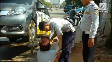 Seorang wanita berteriak histeris pada petugas agar kendaraannya tak diderek. Namun petugas tak bergeming dan menjalankan tugas.