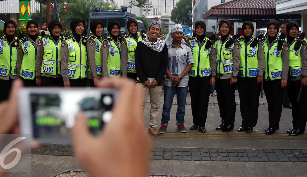 Aksi Damai 4 November diwarnai dengan aksi foto bersama antara pendemo dengan polwan berhijab, Jakarta, Jumat (4/11).  Polwan cantik yang berjaga saat demo ini laris dan memukau para pendemo untuk berfoto bersama. (Liputan6.com/Johan Tallo)