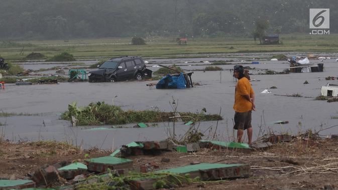 Seorang warga melihat mobil yang terbawa ke tengah sawah setelah tsunami melanda kawasan Anyer, Banten, Minggu (23/12). Tsunami menerjang pantai di Selat Sunda, khususnya di daerah Pandenglang, Lampung Selatan, dan Serang. (Liputan6.com/Angga Yuniar)