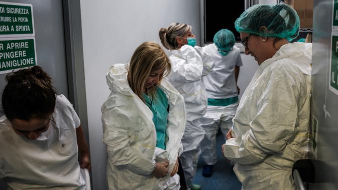 Perawat mengenakan alat pelindung diri untuk memulai shift di rumah sakit Cremona, tenggara Milan, Lombardy pada 12 Maret 2020. Jumlah kematian akibat Covid-19 di Italia sekarang yang tertinggi di dunia, menyalip China tempat wabah ini pertama kali. (Paolo MIRANDA/AFP)