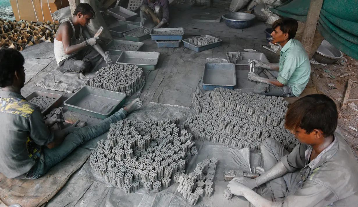 Sejumlah pekerja memasukan bubuk mesiu ketabung kertas untuk membuat petasan yang digunakan dalam festival Diwali di Ahmadabad, India (27/9). Karena tubuh pekerja di penuhi bubuk mesiu seolah terlihat seperti manusia perak. (AP Photo/Ajit Solanki)