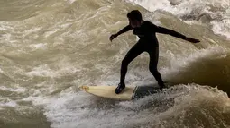 Peselancar berusaha berdiri di atas papan seluncur saat bermain "surfing" di sungai buatan Eisbach di English Garden Munich, Jerman pada 28 Mei 2019. Aliran air sungai Sungai Eisbach yang memiliki lebar 12 meter ini berasal dari Sungai Isar. (Photo by Peter Kneffel/dpa/AFP)