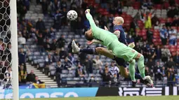 Kiper Republik Ceko, Tomas Vaclik berusaha menepis bola dari sundulan pemain Skotlandia, Lyndon Dykes pada pertandingan grup D Euro 2020 di stadion Hampden Park, Glasgow, Senin (14/6/2021). Dengan kemenangan ini, Ceko menggeser Inggris dari puncak klasemen sementara. (Stu Forster, Pool via AP)