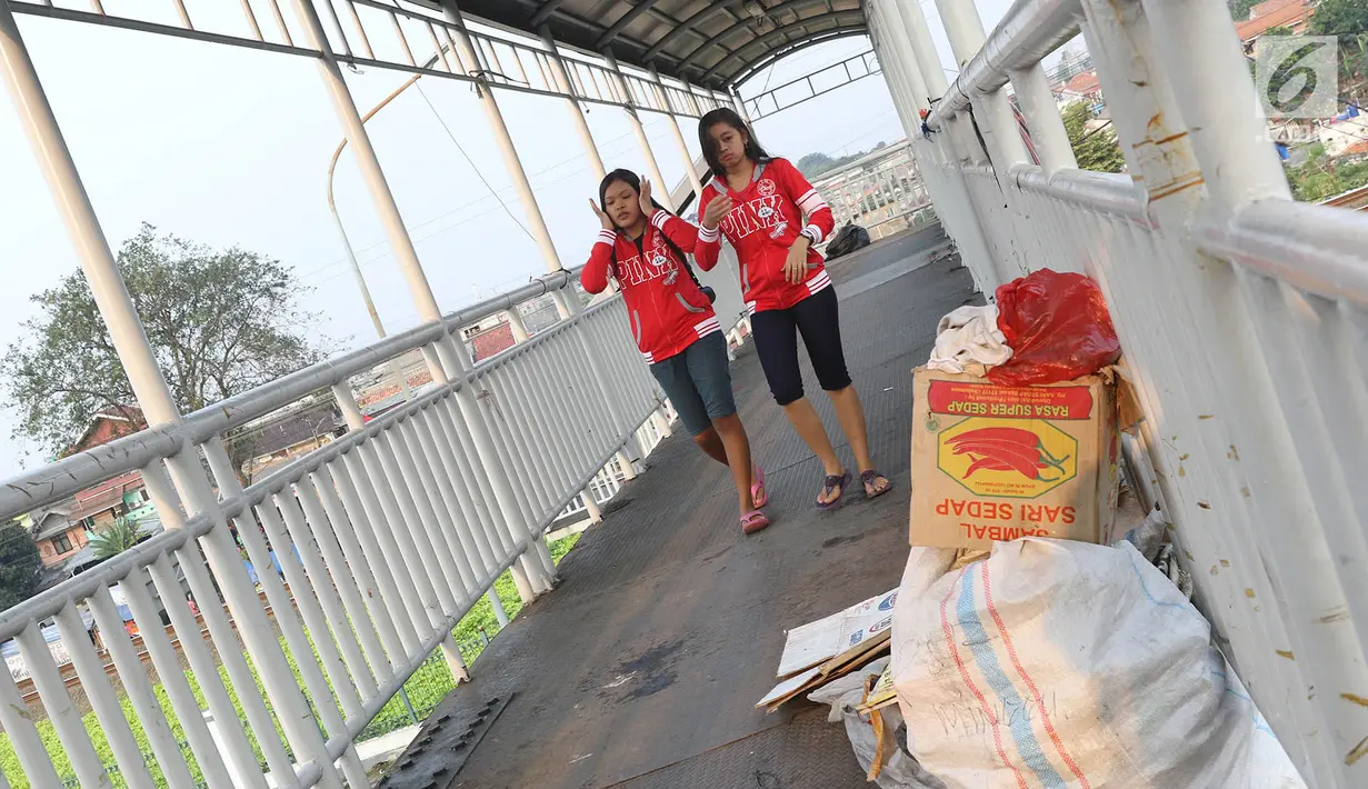 Dua orang wanita melintas di jembatan penyeberangan orang di Jakarta, Minggu (6/8). Dinas Bina Marga DKI Jakarta akan merevitalisasi JPO dengan anggaran Rp10 miliar sesuai dengan APBD 2017. (Liputan6.com/Immanuel Antonius)