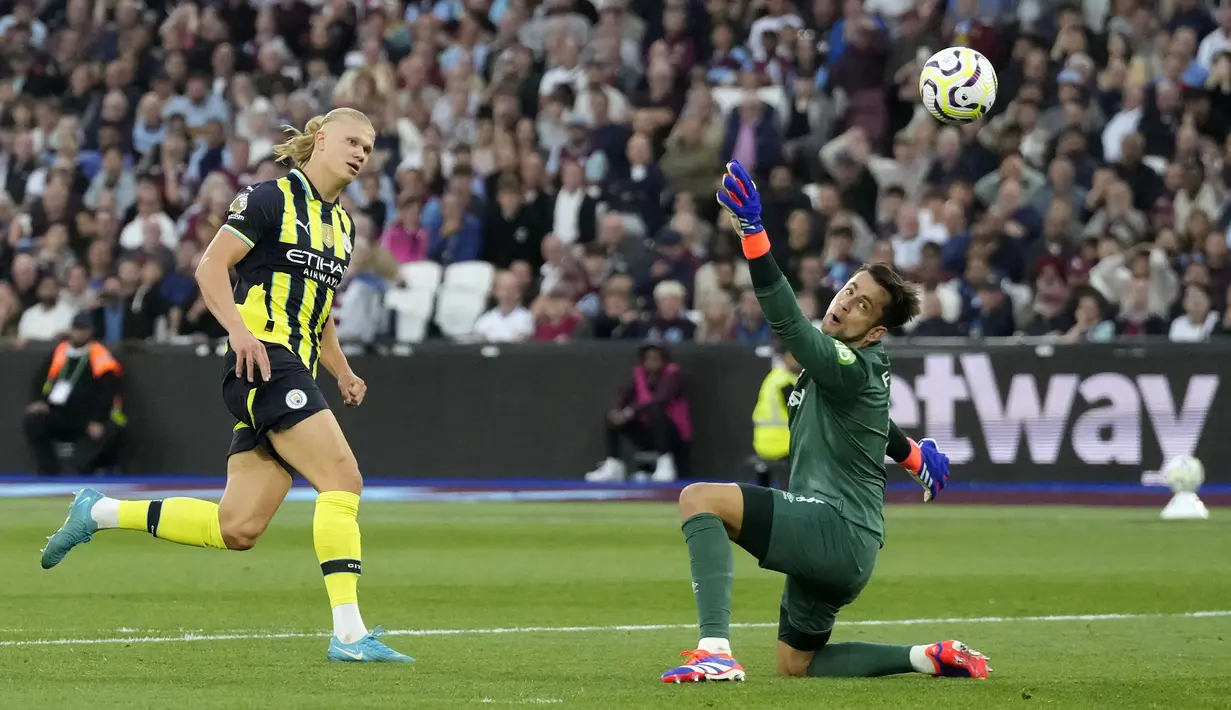 Pemain Manchester City, Erling Haaland (kiri) mencetak gol ke gawang West Ham United yang dijaga oleh Lukasz Fabianski pada laga lanjutan Liga Inggris 2024/2025 di London Stadium, London, Inggris, Sabtu (31/08/2024) waktu setempat. (AP Photo/Frank Augstein)