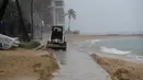Traktor kecil mendorong pasir dari jalan setapak di Pantai Waikiki, Honolulu  (6/12/2021). Pihak berwenang mengatakan kondisi yang berpotensi lebih buruk ke depannya. (AP Photo/Caleb Jones)