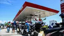 Pengendara sepeda motor mengantre untuk mendapatkan bahan bakar minyak (BBM) di SPBU Kota Palu, Sulawesi Tengah, Senin (1/10). Antrean bahkan mengular hingga ke jalan raya. (Jewel Samad/AFP)
