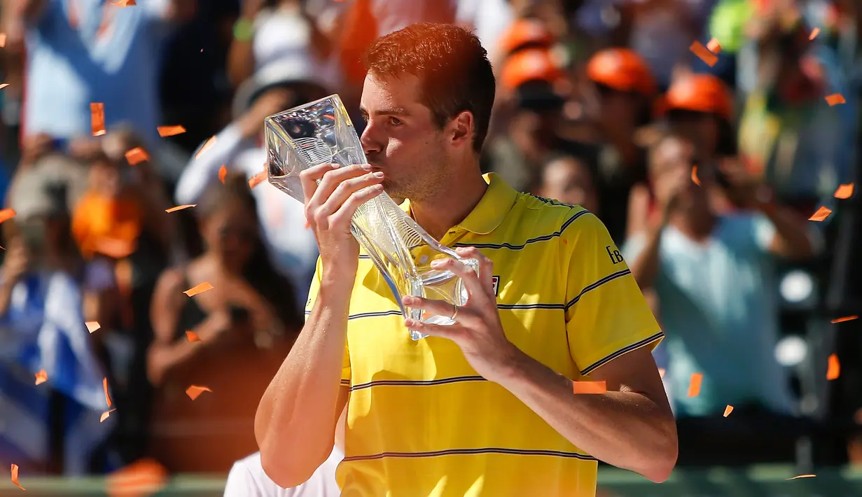 Petenis AS, John Isner mencium trofi usai meraih gelar juara Miami Terbuka 2018 di Key Biscayne, Minggu (1/4). Pada laga final yang menegangkan itu, Isner sukses menaklukkan petenis Jerman Alexander Zverev 6-7, 6-4, 6-4. (Michael Reaves/GETTY IMAGES/AFP)