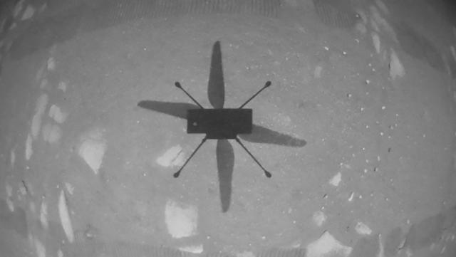 Helikopter Ingenuity melayang di atas permukaan planet Mars saat penerbangan pertama bertenaga dan terkontrol di planet lain pada 19 April 2021. h(Handout/NASA/JPL-CALTECH/AFP)