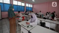 Guru mengajar saat uji coba pembelajaran tatap muka (PTM) terbatas di SMAN 1 Kota Tangerang, Banten, Senin (6/9/2021). Dinas Pendidikan Provinsi Banten uji coba PTM di SMA di Kota Tangerang secara terbatas dengan sistem bergiliran dan menerapkan protokol kesehatan ketat. (Liputan6.com/Angga Yuniar)