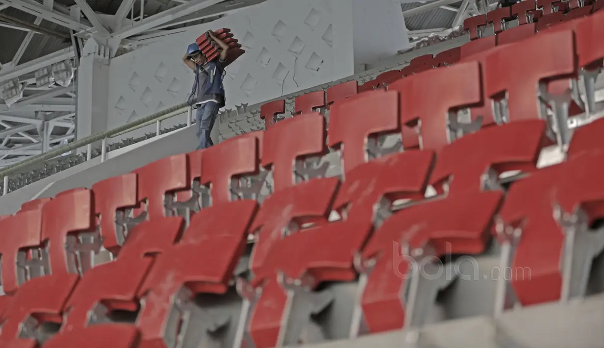 Seorang pekerja membawa kursi untuk renovasi Stadion Utama Gelora Bung Karno di Senayan, Jakarta, Selasa (23/5/2017). Renovasi untuk persiapan Asian Games 2018. (Bola.com/Nicklas Hanoatubun)