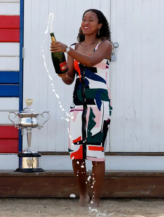 Petenis Jepang, Naomi Osaka menyemprotkan sampanye menyemprotkan sampanye merayakan gelar juara tunggal putri Australia Terbuka 2019 di Pantai Brighton Melbourne, Australia, Minggu (27/1). (AP Photo/Kin Cheung)