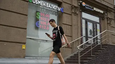 Seorang pria berjalan melewati kantor penukaran mata uang di Moskow, Rusia, Senin, 14 Agustus 2023.  (AP Photo/Alexander Zemlianichenko)