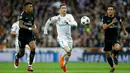 Pemain Real Madrid, Cristiano Ronaldo mengejar bola dengan kawalan pemain Paris Saint-Germain pada leg pertama babak 16 besar Liga Champions di Stadion Santiago Bernabeu, Rabu (14/2). Dua dari tiga gol Real Madrid disumbangkan Ronaldo. (AP/Paul White)