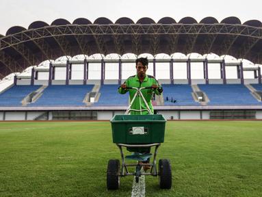 Pekerja sedang melakukan pemupukan rumput di Stadion Indomilk Arena, Tangerang pada Rabu (25/08/2021) sore WIB. Hal tersebut merupakan salah satu bentuk perawatan dan persiapan stadion untuk menyambut kompetisi BRI Liga 1 yang akan segera bergulir. (Foto: Bola.com/Bagaskara Lazuardi)