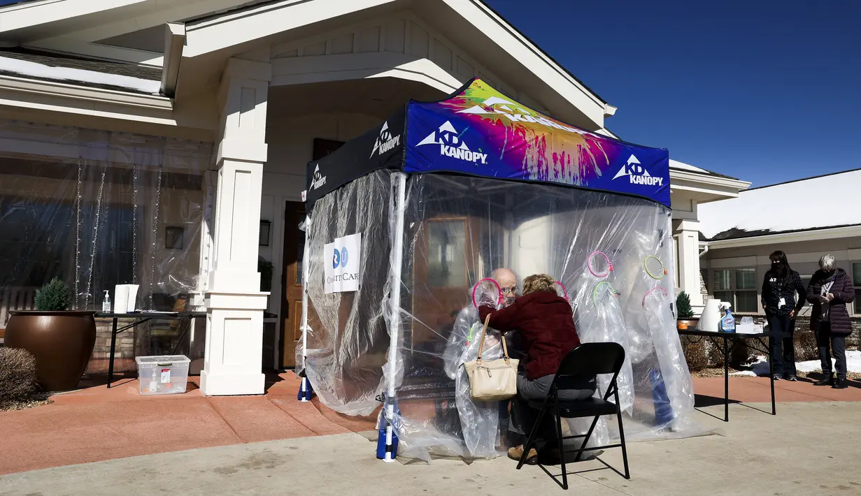 Diane Rossi (kanan) memeluk suaminya melalui tenda pelukan di komunitas Crossroads Senior Living di Lakewood, Colorado, Jumat (26/2/2021). Tenda tersebut memungkinkan anggota keluarga untuk terhubung secara fisik satu sama lain untuk pertama kalinya sejak corona (Michael Ciaglo/Getty Images/AFP)