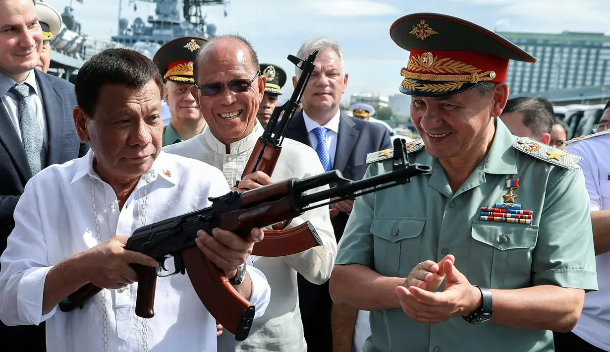 Presiden Filipina Rodrigo Duterte bersama Menhan Rusia, Sergei Shoigu (kanan) memegang senapan serbu AK-47 sumbangan dari Rusia di atas kapal perusak Rusia Admiral Panteleyev di pelabuhan Metro Manila, Filipina (25/10). (AFP Photo/Robinson Ninal)