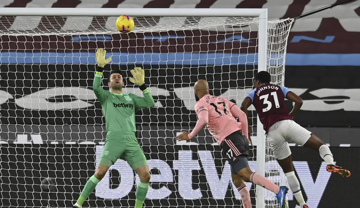 Striker Sheffield United, David McGoldrick (tengah) melepaskan sundulan yang dapat diantisipasi kiper West Ham United, Lukasz Fabianski dalam laga lanjutan Liga Inggris 2020/21 pekan ke-24 di London Stadium, London, Senin (15/2/2021). Sheffield United kalah 0-3 dari West Ham. (AP/Glyn Kirk/Pool)