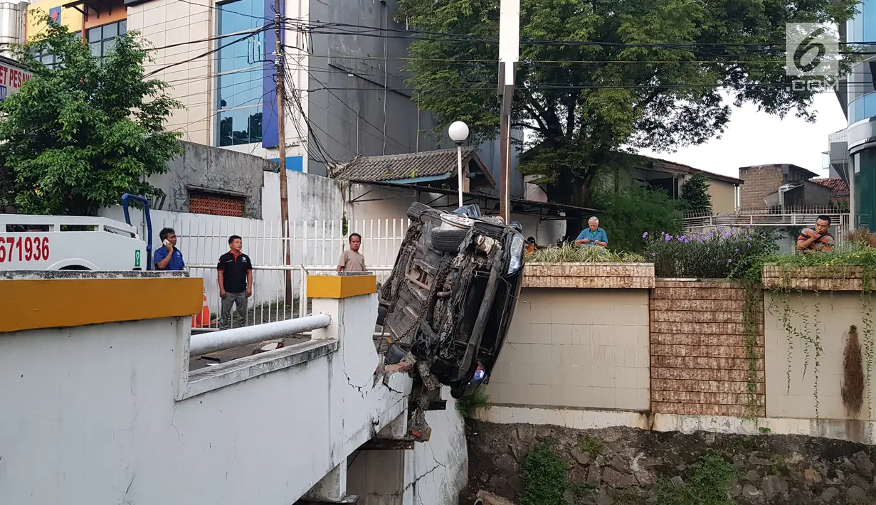 Kondisi mobil yang hilang kendali dan tersangkut di antara tembok pembatas sungai di kawasan Pasar Minggu, Jakarta Selatan, Sabtu (8/6/2019) pagi. Jajaran Satlantas Polres Jaksel masih melakukan penyelidikan dan mencari keberadaan pengemudi yang menghilang. (Liputan6.com/Herman Zakharia)