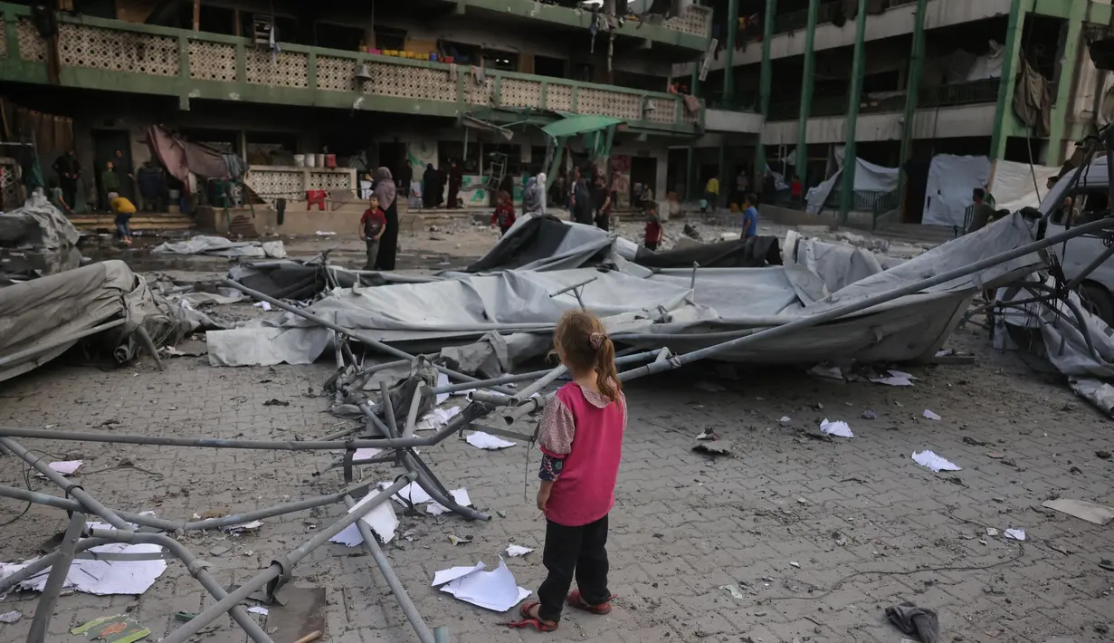 Seorang anak perempuan Palestina melihat reruntuhan sekolah Fatima Bint Asad yang dihantam serangan semalam oleh Israel di Jabalia, Jalur Gaza utara, Senin 12 Mei 2025. (Bashar TALEB/AFP)