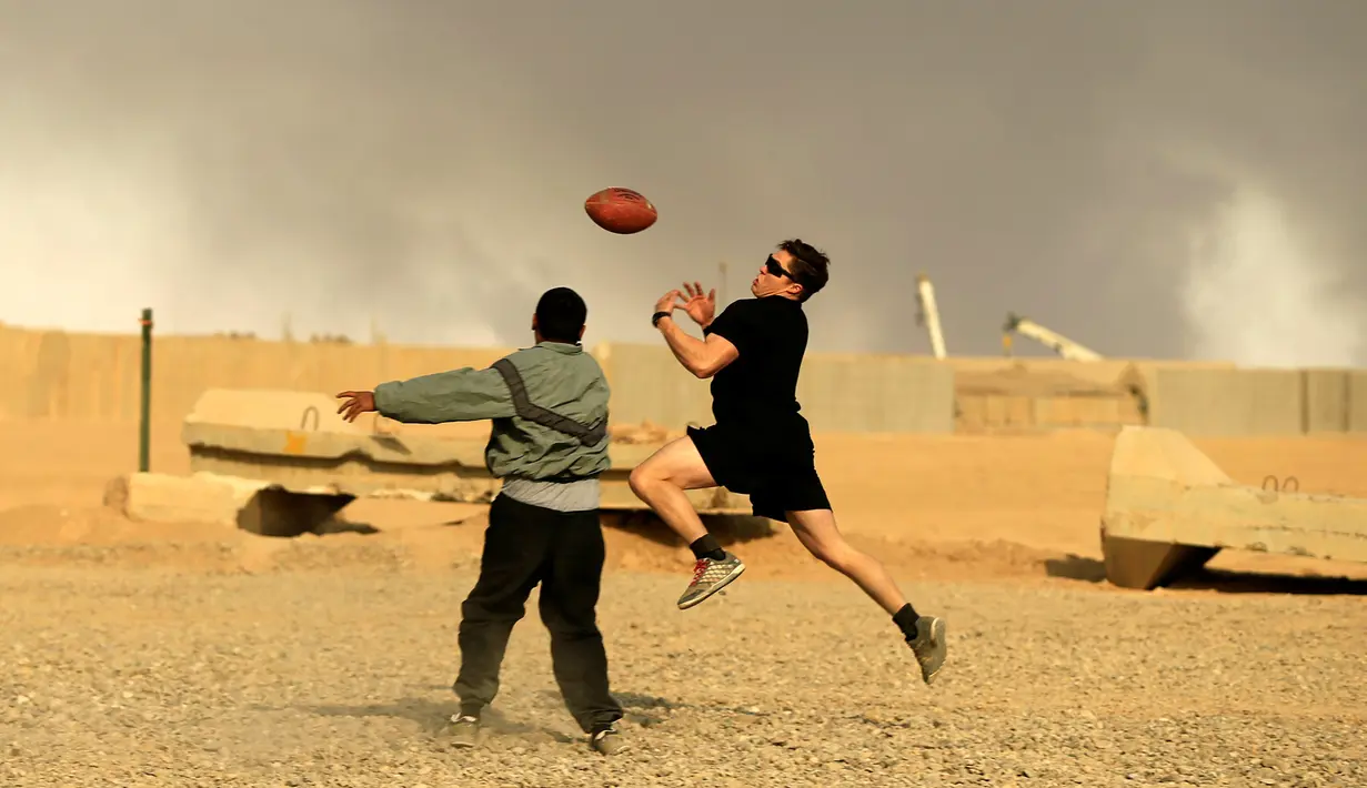 Tentara AS berusaha menangkap bola saat bermain American Football pada Thanksgiving di dalam pangkalan militer AS di Qayyara, selatan Mosul, Irak (24/141). (REUTERS/Thaier Al-Sudani)