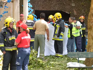 Petugas pemadam kebakaran setempat mengevakuasi korban pohon tumbang di Funchal, Portugal (15/8). Sedikitnya 11 orang tewas akibat tertimpa pohon tumbang tepat ketika berlangsung festival keagamaan. (AFP Photo/Rui Silva)