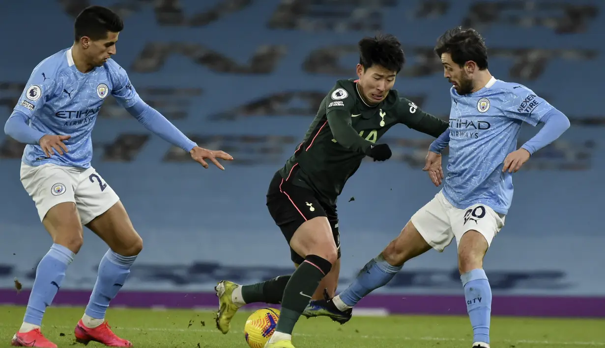 Penyerang Tottenham Hotspur, Son Heung-min berusaha melewati dua pemain Mancheste City, Joao Cancelo dan Bernardo Silva pada pertandingan Liga Inggris di Stadion Etihad, Inggris, Minggu (14/2/2021).  Tottenham Hotspur menduduki peringkat kedelapan klasemen dengan 36 angka. (AP Photo/Rui Vieira)