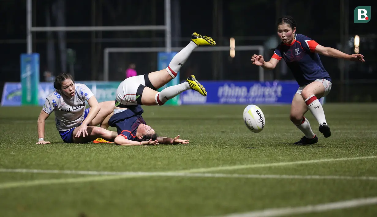 Pemain tim ruby putri Mongolia, Dejidmaa Uuganbayar (tengah) terpelanting usai dijatuhkan oleh pemain tim rugby Guam, Olivia Elliott saat laga Asia Rugby Sevens Trophy 2022 melawan tim rugby putri Arab Saudi yang berlangsung di GBK Rugby Field, Jakarta, Sabtu (06/08/2022). (Bola.com/Bagaskara Lazuardi)