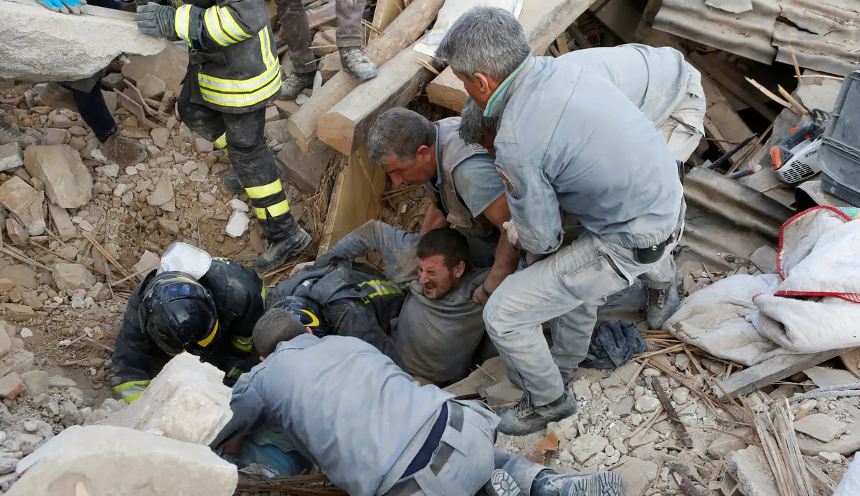 Sejumlah petugas dibantu warga menolong seorang pria yang tertimbun reruntuhan bangunan akibat gempa di Amatrice, Italia tengah, (24/8). Sekitar enam orang tewas akibat gempa tersebu. (REUTERS/Remo Casilli)