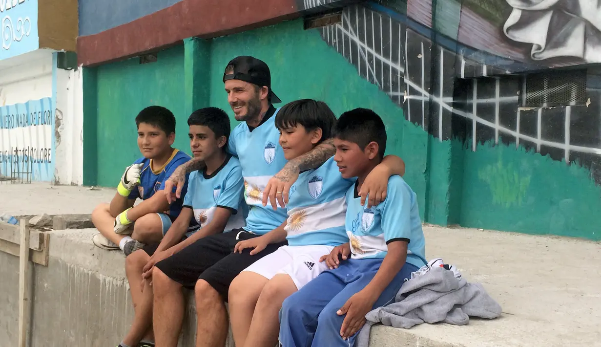 Mantan kapten Timnas Inggris, David Beckham bercengkrama dengan anak-anak di kawasan pemukiman kumuh 1-11-14 di Buenos Aires, Senin (9/11). Beckham berada Argentina untuk membuat film dokumenter tentang sepak bola. (AFP/FIXER-Argentina/Macarena GAGLIARD)