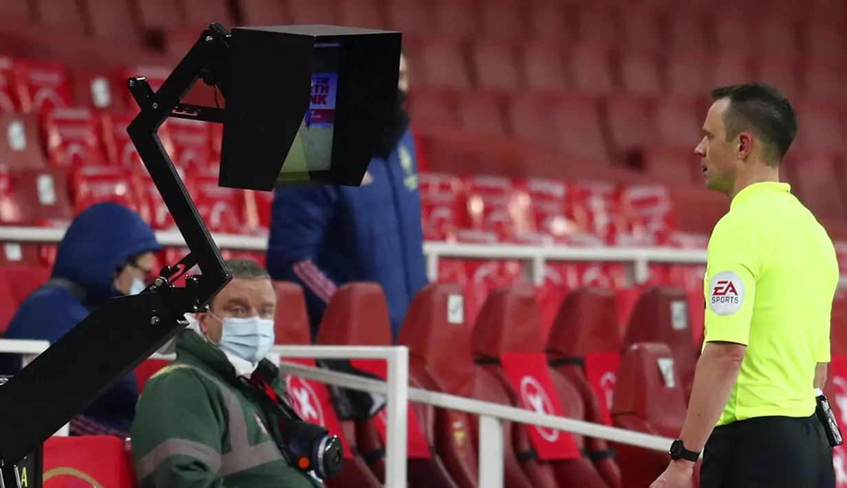 Wasit Stuart Attwell melihat monitor VAR pada pertandingan Liga Inggris antara Arsenal melawan Leeds United di Emirates Stadium, London, Inggris, Minggu (14/2/2021). Arsenal menyikat Leeds United 4-2 dengan hattrick dari Pierre-Emerick Aubameyang. (Catherine Ivill/Pool via AP)