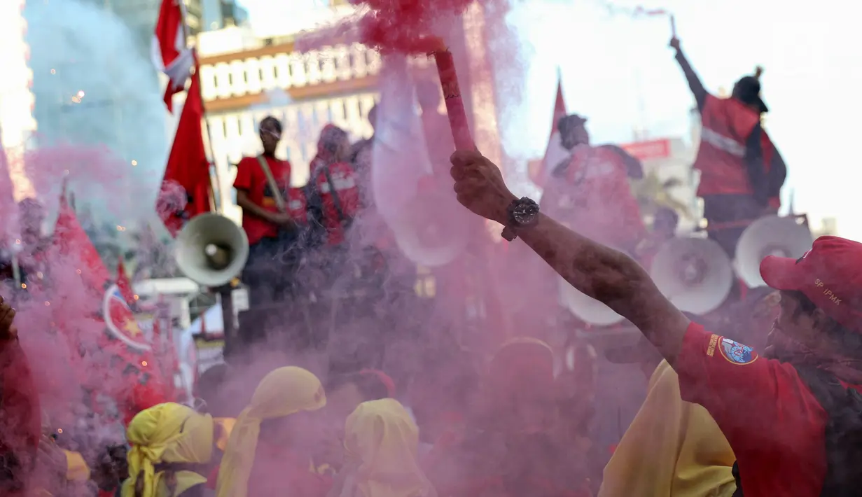 Sejumlah buruh menyalakan bom asap saat menutup aksi Hari Buruh Internasional di Jalan Medan Merdeka Barat, Jakarta, Rabu (5/1/2019). Aksi May Day 2019 di Jakarta ditutup oleh buruh dengan menyalakan kembang api sebagai simbol berjalannya demo dengan damai. (Liputan6.com/Helmi Fithriansyah)