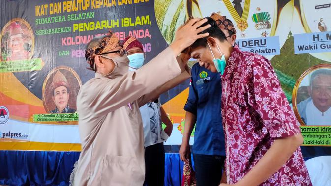 Pemasangan ikat kepala tanjak, yang sudah dibuat oleh Sejarahwan dan Budayawan Sumsel Raden Muhammad Ali Hanafiah, saat acara Seminar Sehari di Museum Negeri Sumsel (Liputan6.com / Nefri Inge)
