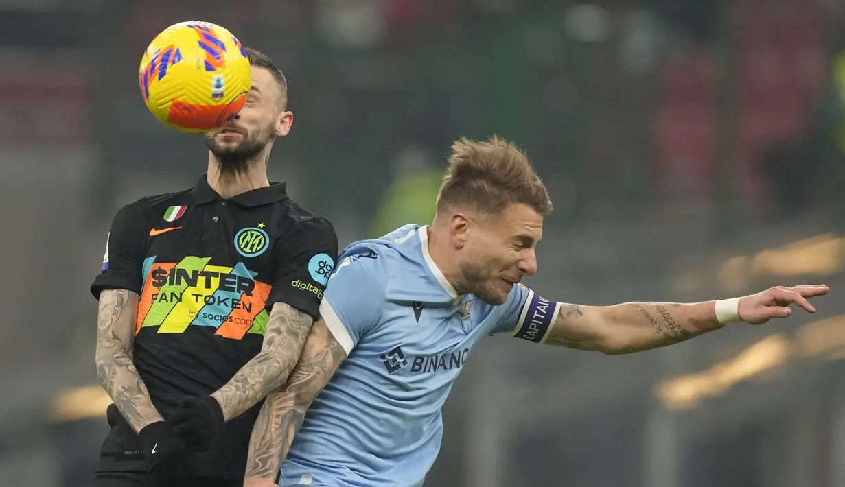 Gelandang Inter Milan, Marcelo Brozovic berebut bola dengan penyerang Lazio, Ciro Immobile pada pertandingan Liga Serie A Italia di Stadion San Siro, di Milan, Italia, Senin (10/1/2022). Dengan hasil ini, Inter Milan kembali memuncaki klasemen sementara dengan 49 poin. (AP Photo/Antonio Calani)