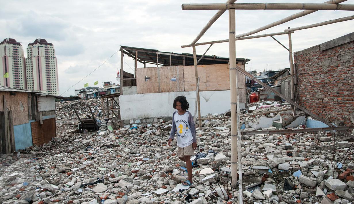 Seorang bocah melintas di dekat puing-puing di Kampung Akuarium, Penjaringan, Jakarta Utara, Senin (30/1). Saat ini ratusan warga masih tinggal di lokasi yang telah digusur oleh Pemprov DKI. (Liputan6.com/Gempur M Surya)