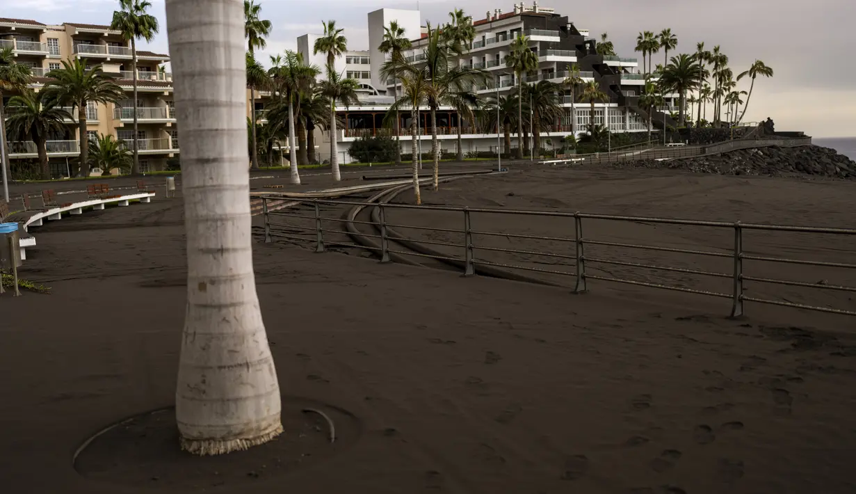 Abu gunung berapi Cumbre Vieja menutupi kawasan pejalan kaki desa Puerto Naos di pulau Canary La Palma, Spanyol, Rabu (27/10/2021). Penduduk di Pulau La Palma menghadapi kemungkinkan gempa yang lebih kuat yang bisa memperparah kerusakan oleh muntahan lava gunung tersebut. (AP Photo/Emilio Morenatti)