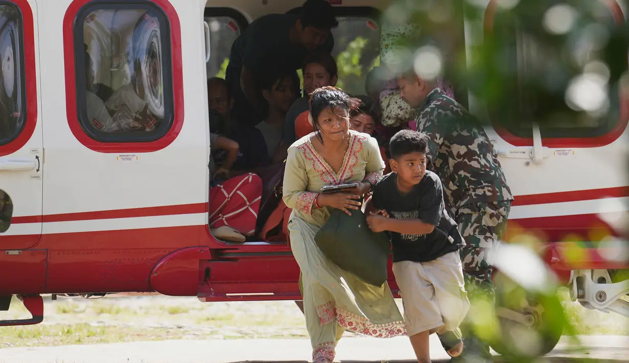 Tentara membantu sebuah keluarga turun dari helikopter setelah mereka diselamatkan dari wilayah yang terdampak banjir bandang di distrik Nuwakot, Nepal, Jumat, 28 Agustus 2026. (Foto AP/Rajesh Kumar Singh)