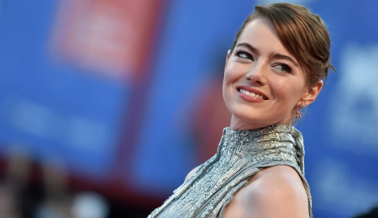 Aktris Emma Stone tersenyum saat tiba menghadiri pembukaan Festival Film Venice ke-73 di Italia, (31/8). Menggunakan gaun metalik dari Atelier Versace Emma terlihat cantik dan memukau. (AFP Photo/TIZIANA FABI)